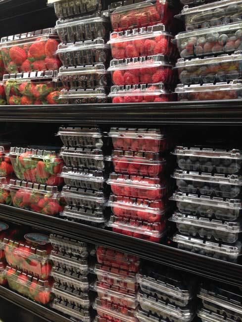 Photo of various berries displayed in clamshells in a supermarket produce section