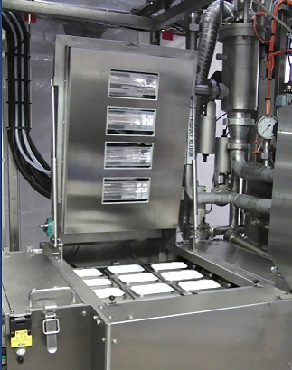 A large stainless steel machine with its lid raised and nine white rectangular food containers visible inside.
